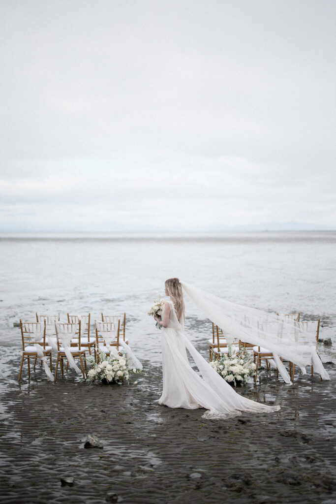 long view of bride on beach with Chiavari chairs in Vancouver