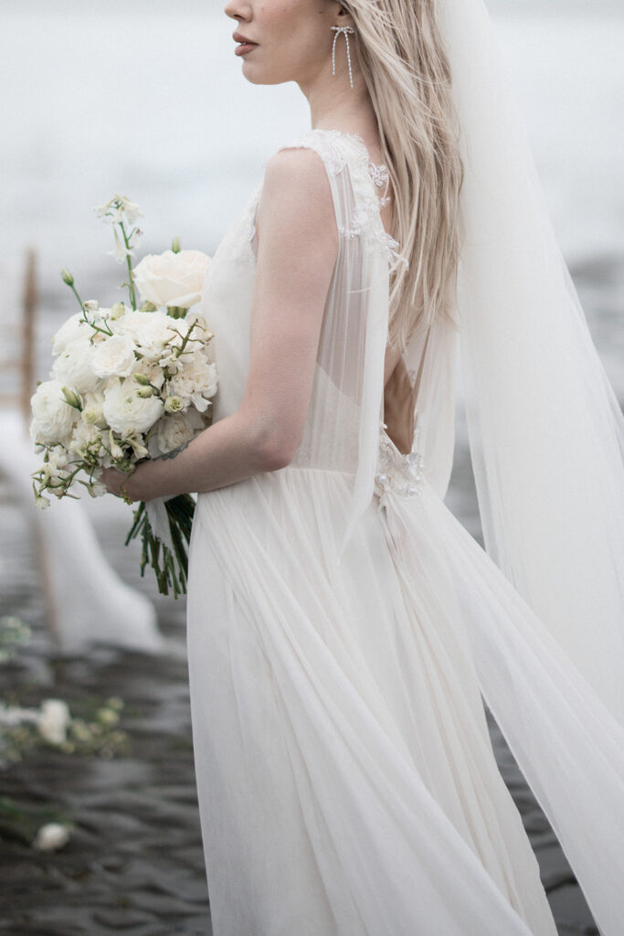 Jenny Yoo bride holds white roses on Vancouver beach