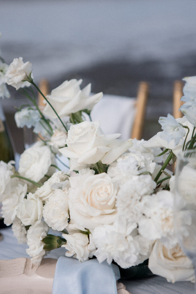 white roses and light blue decor with gold candle holders on reception table