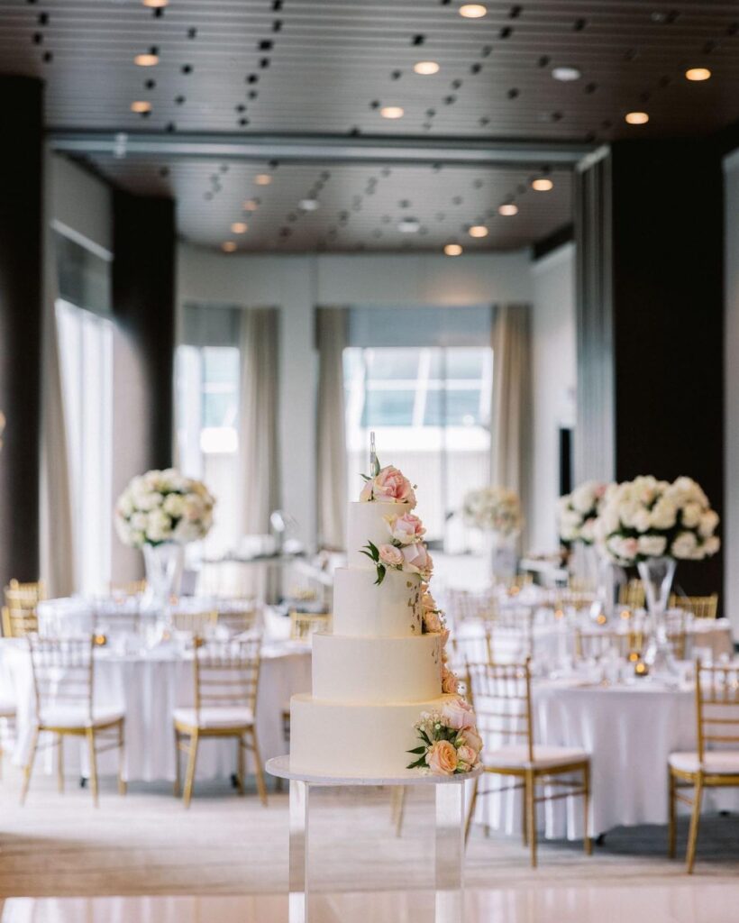 cake sits among white reception tables PROLINE vancouver