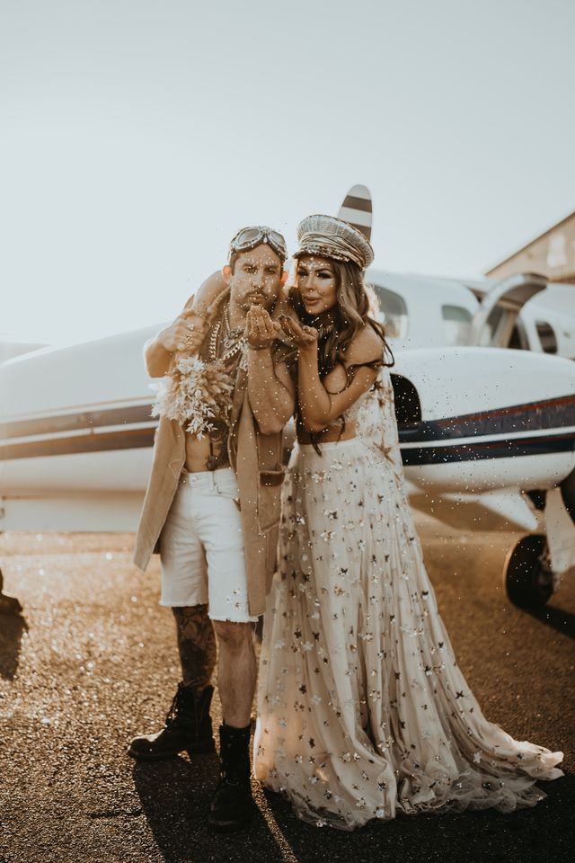 Bride and groom embrace next to Cessna airplane