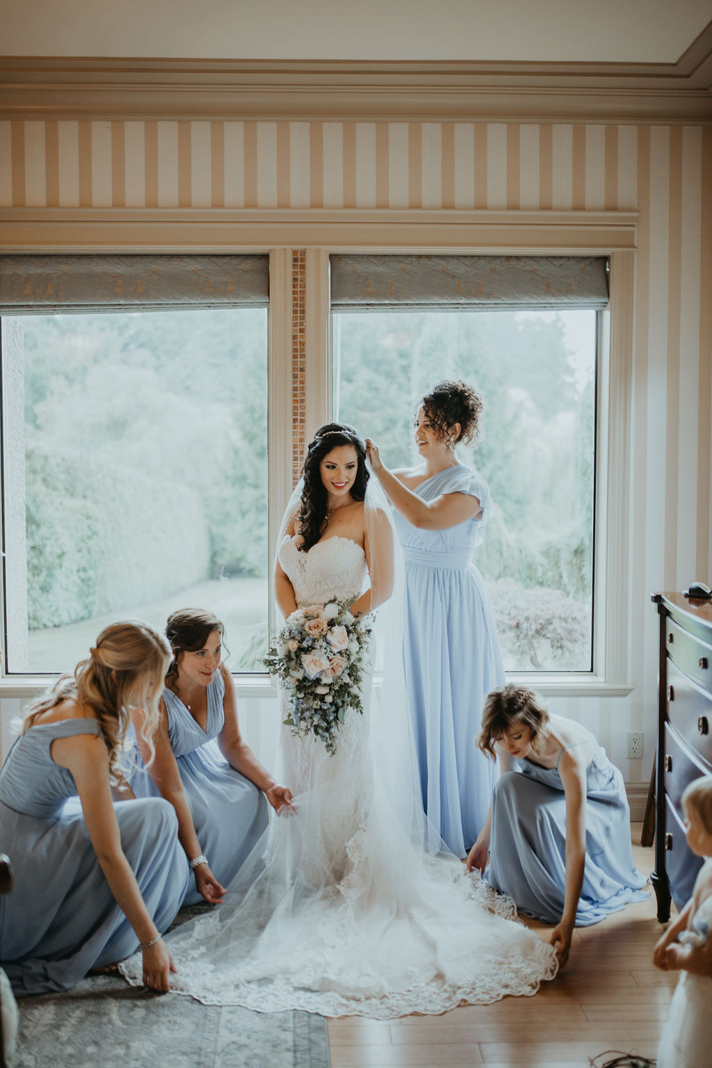 Bridesmaids help bride with gown by Rivkah Photo