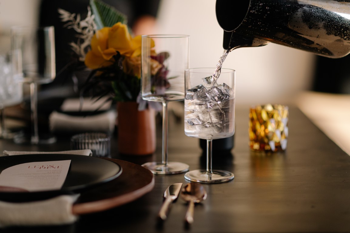 Wine glass reflects on black table by Mathis Fast Photography