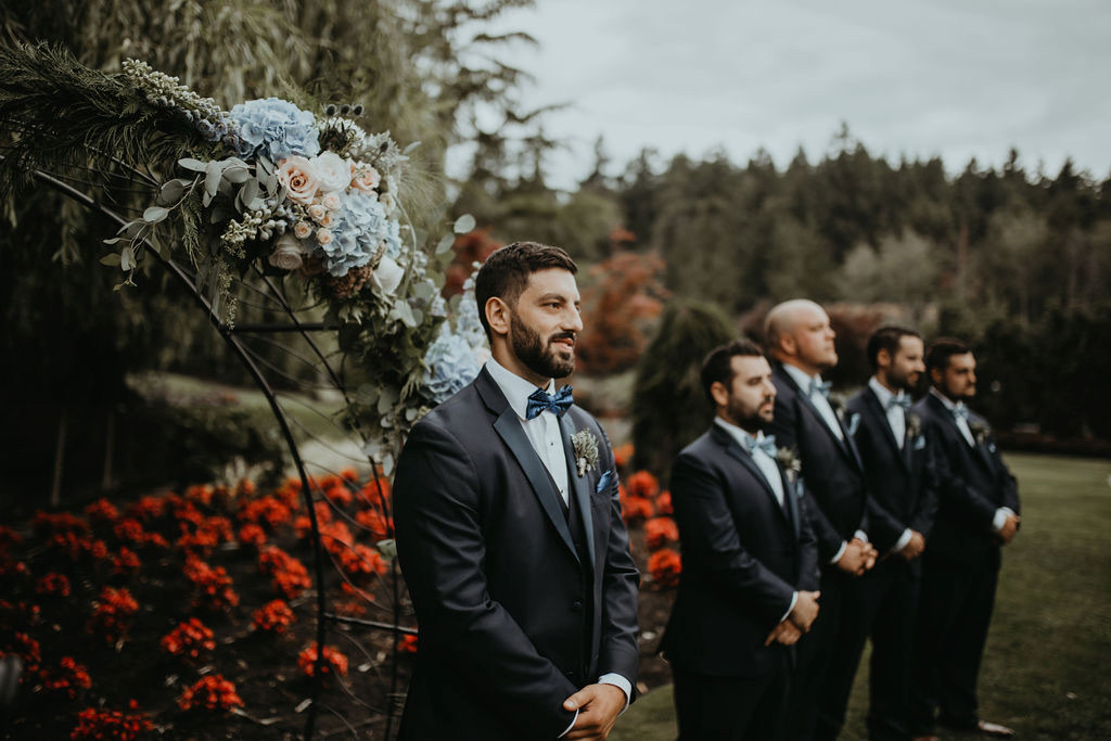 Groom waits in front of flowers by Rivkah Photo