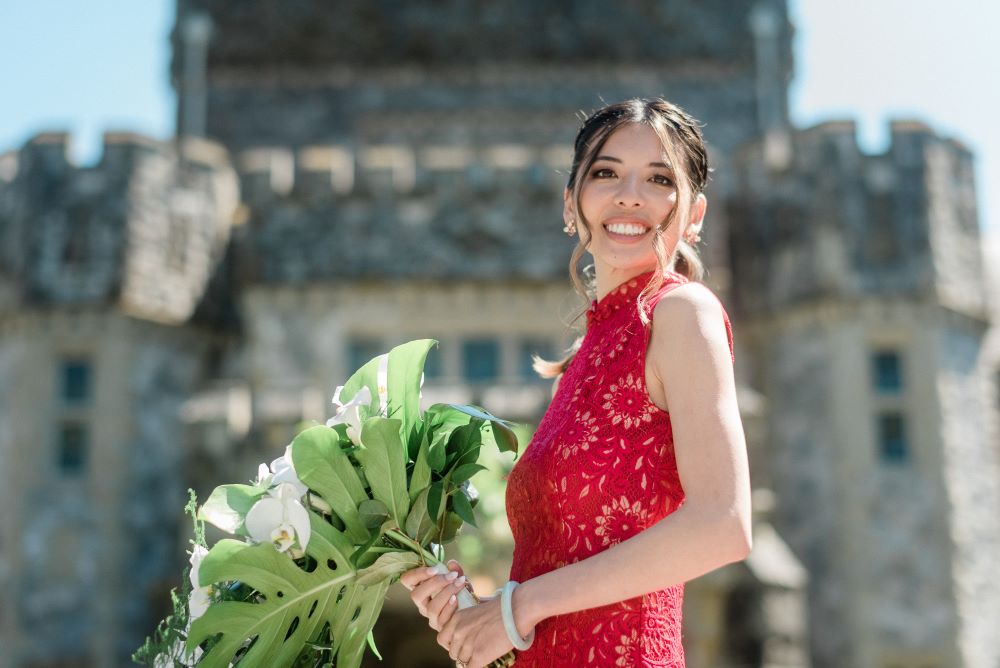 Bride in red lace gown smiles and holds bouquet