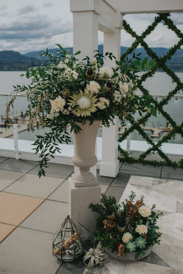 White flowers and greenery in grecian urn at wedding ceremony