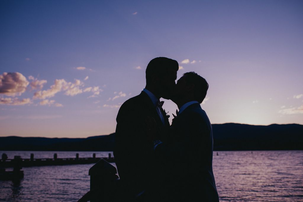 Grooms kiss on lake dock in Kelowna