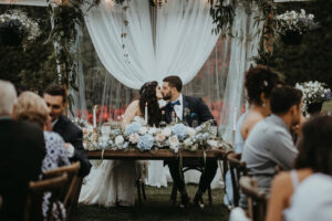 Newlyweds kiss at sweetheart table by Rivkah Photo