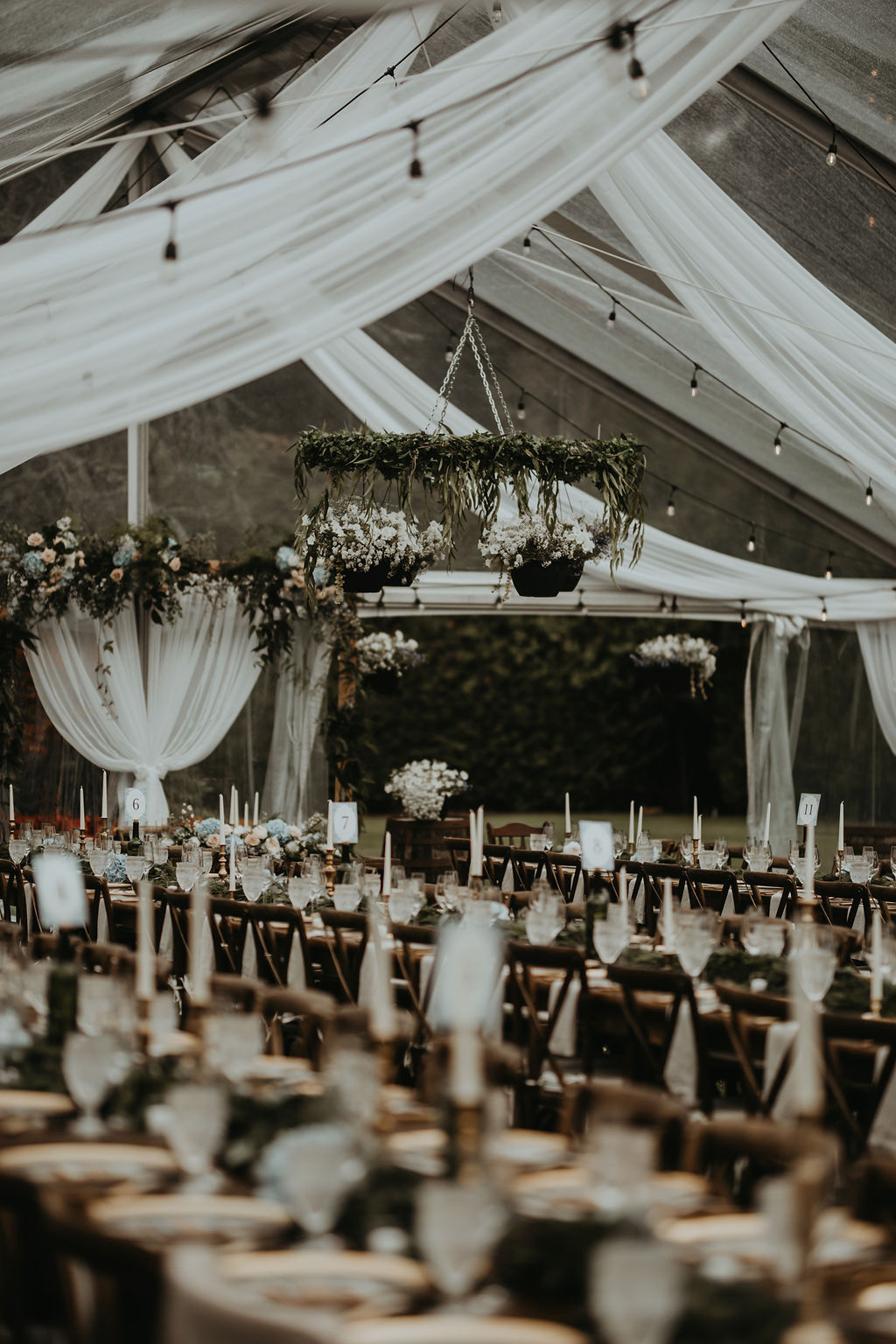 Draped wedding tent with chandeliers and tables by Decorate Victoria