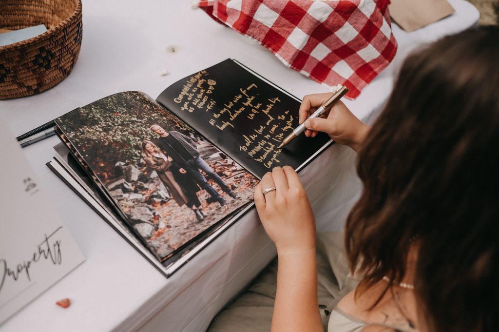 Guest signs photo book at Poet's Cove wedding