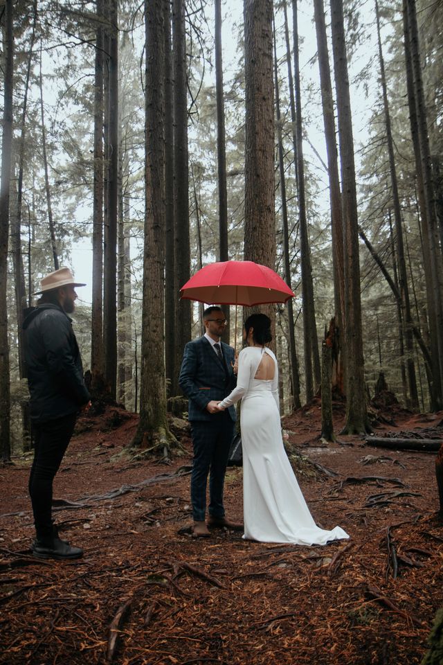 A rainy wedding ceremony in rainforest under red umbrella