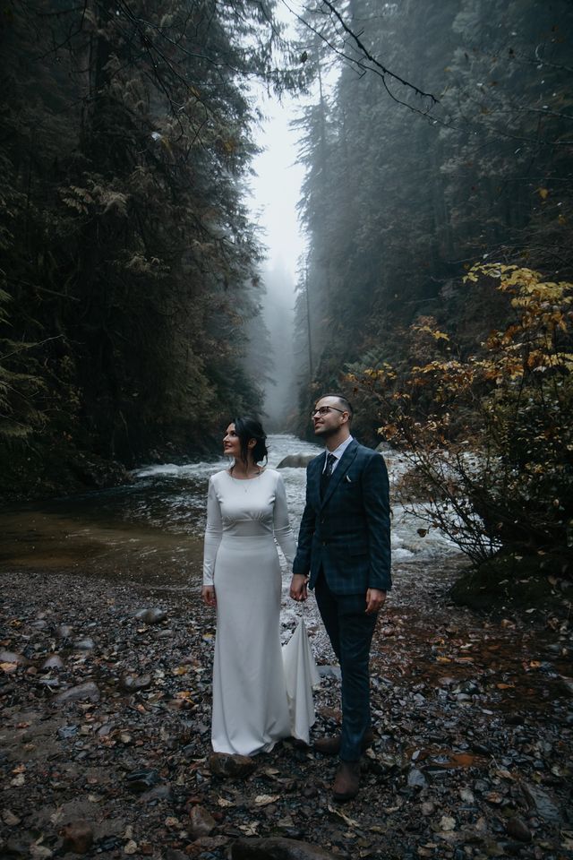 Bride and groom in front of BC river forest