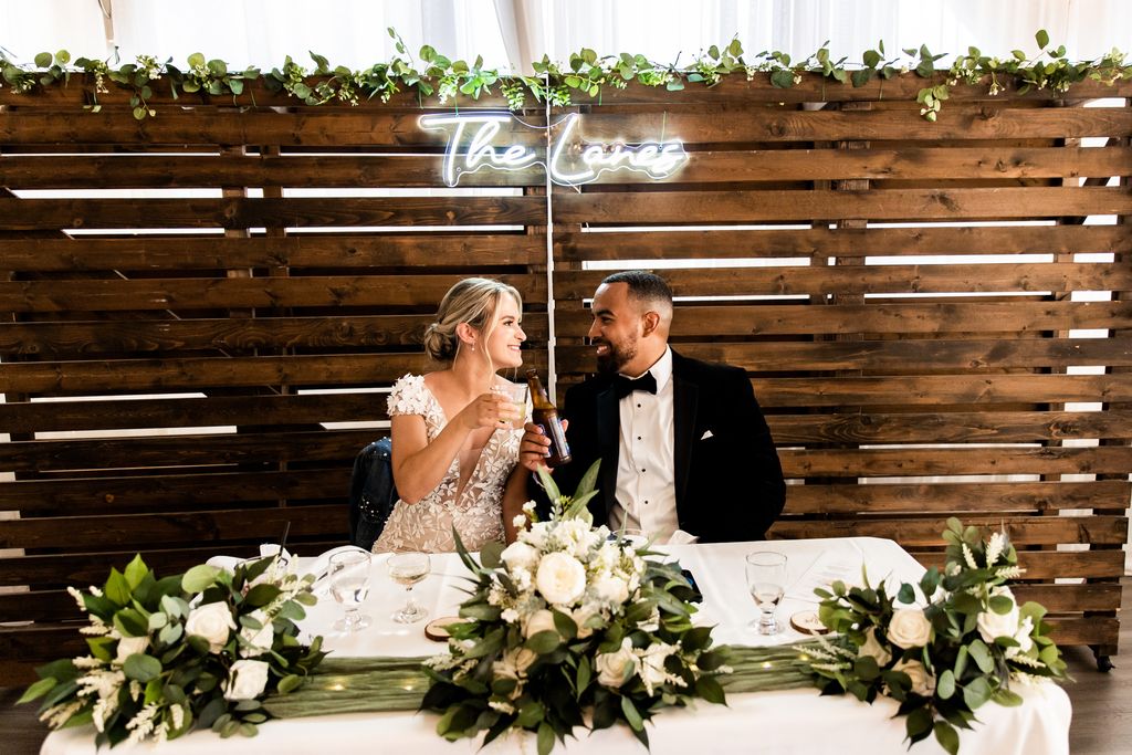 newlyweds at sweetheart table with white and green flowers