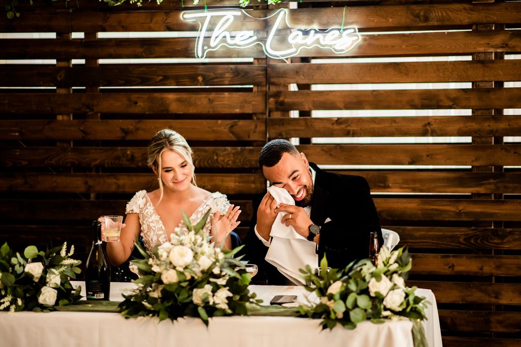 Newlyweds at sweetheart table with sign