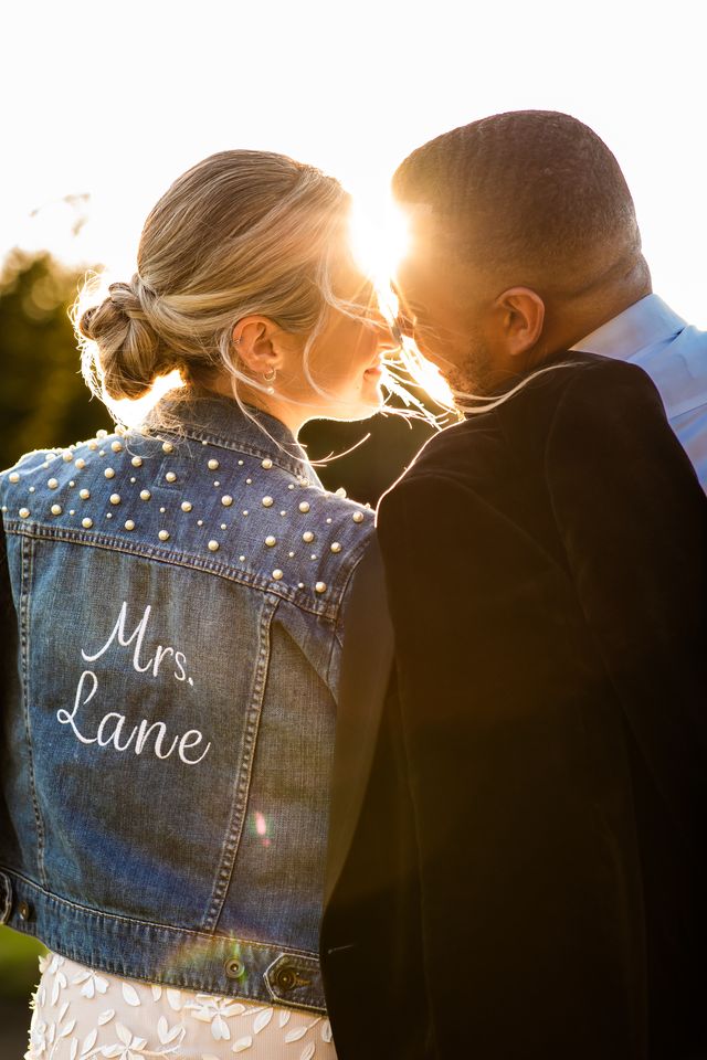 Newlyweds in sunset with bride in logo jean jacket