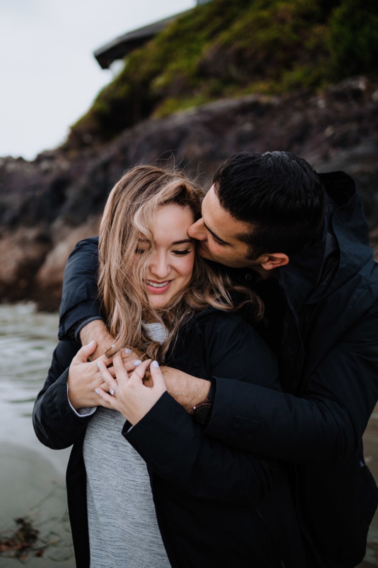 Engaged couple embrace on Tofino rocks