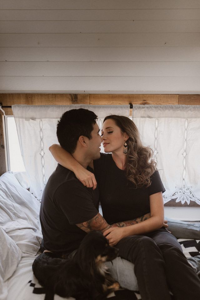 couple in black tshirts sit on retro trailer bed