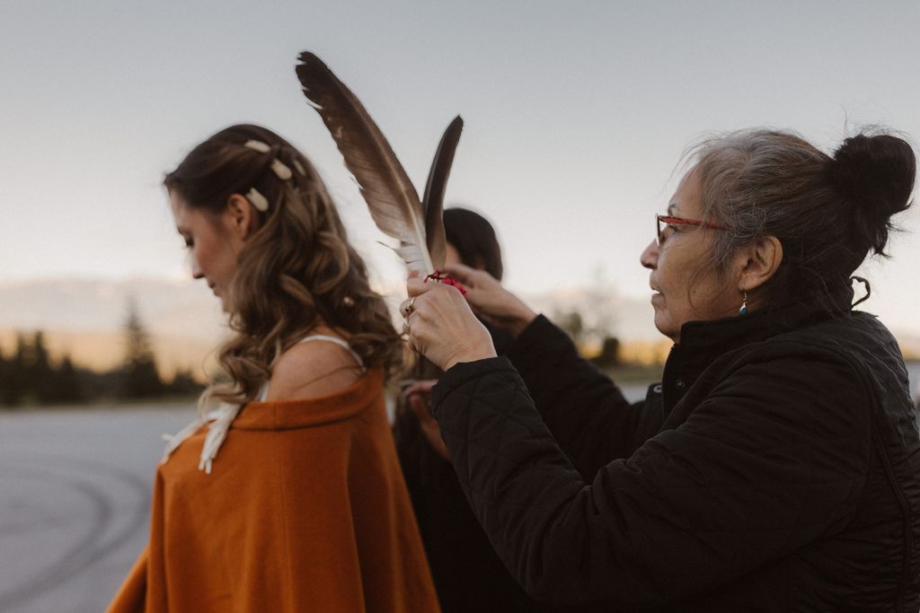 Elder woman placed feather in indigenous bride's hair