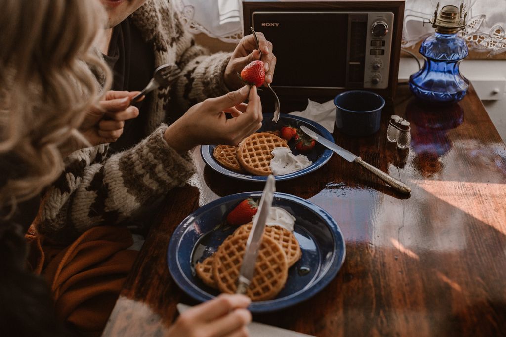 couple puts syrup on pancakes on blue plates