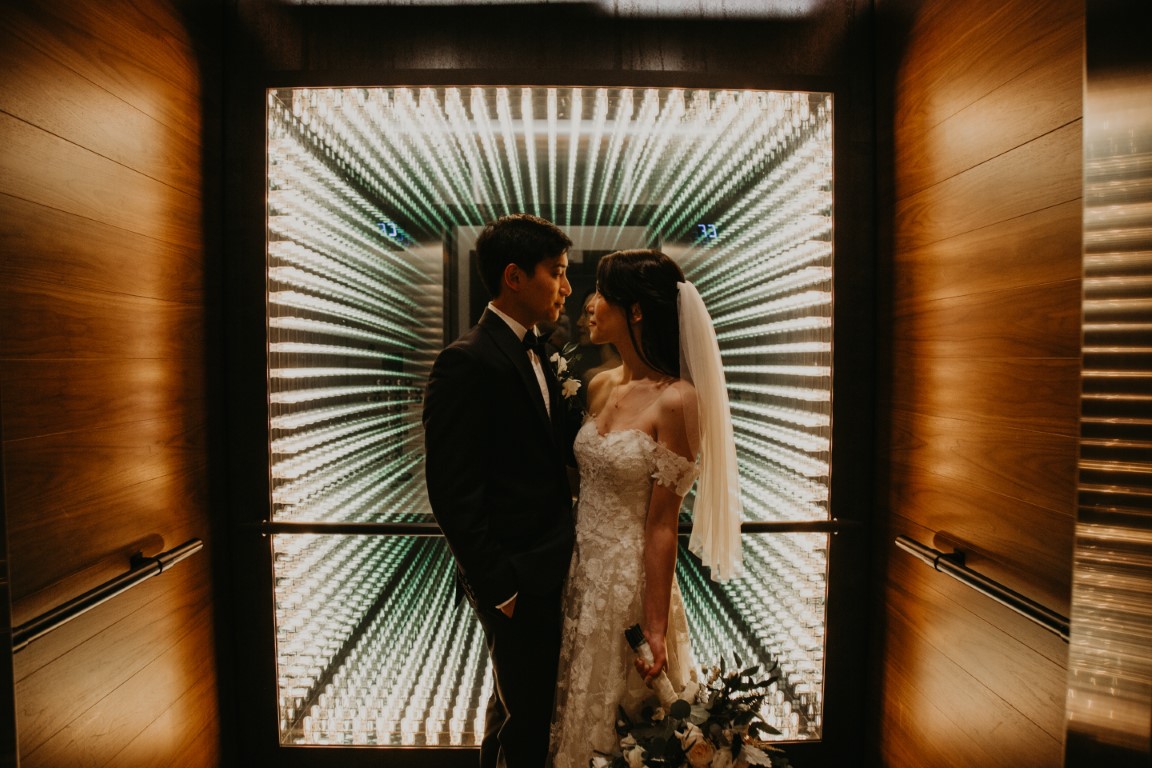 Newlyweds in front of urban wall in Vancouver