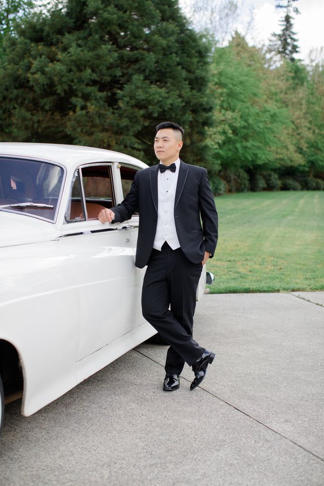 Groom poses by vintage car