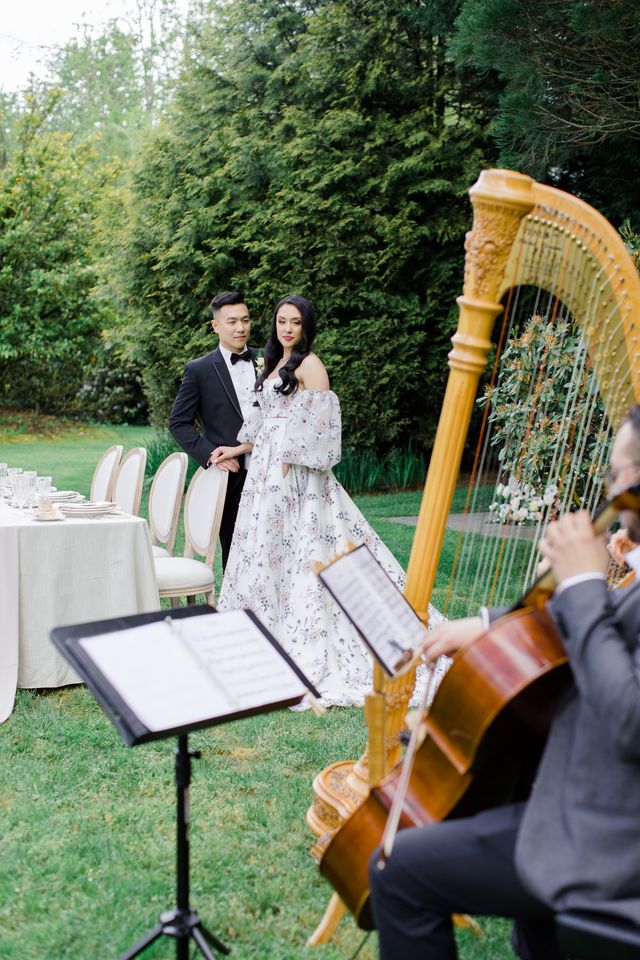 Bride and groom listen to harpist in garden