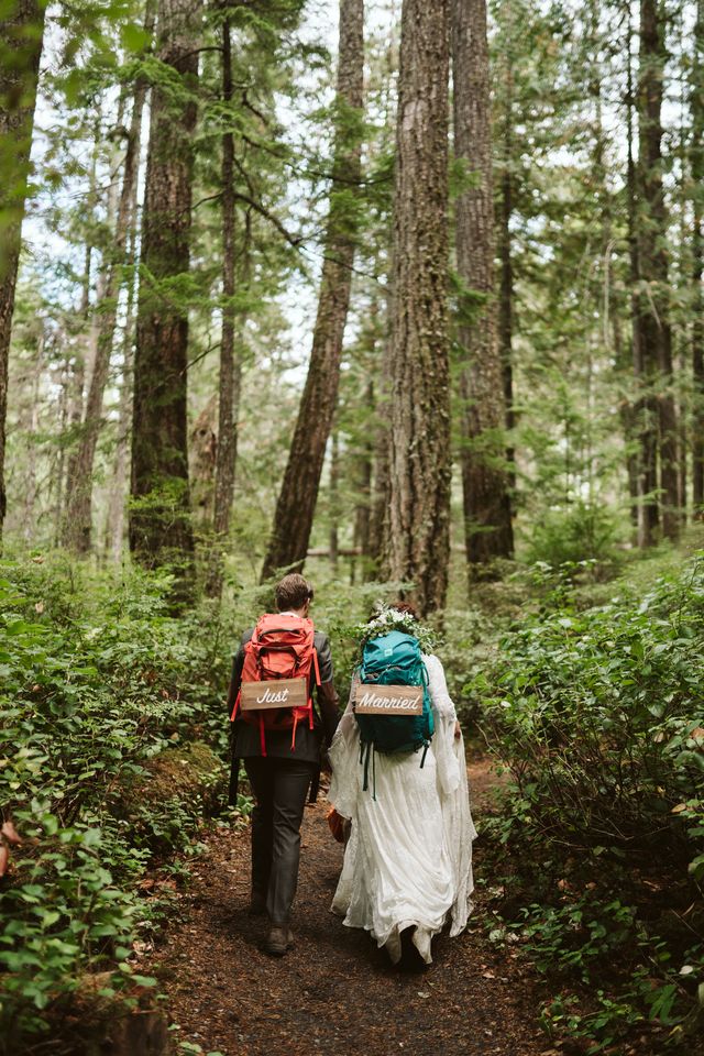 newlyweds walk forest path with backpacks