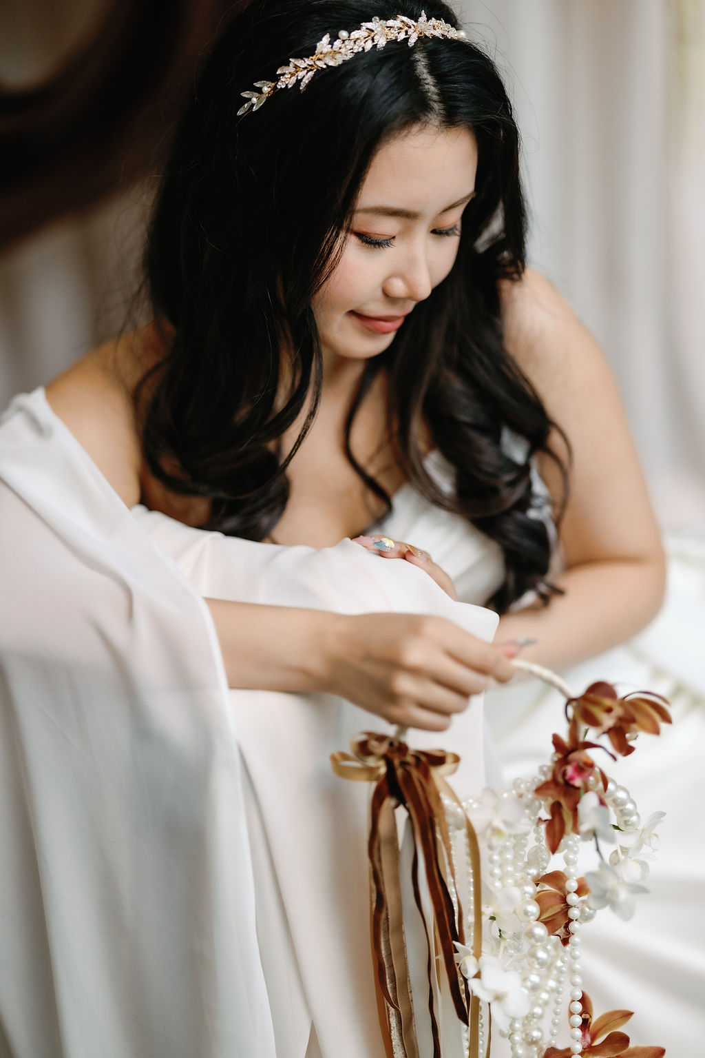 bride gazes at unique bouquet with orange orchids and ribbons