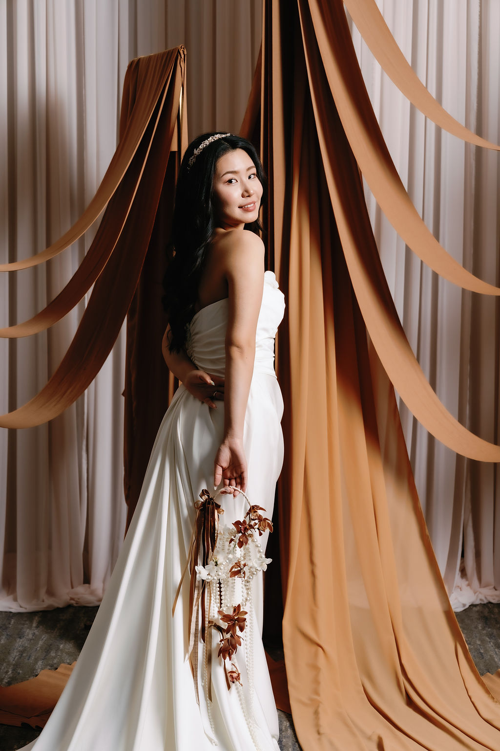 Bride in front of gold ribbon drapery by Bespoke Decor