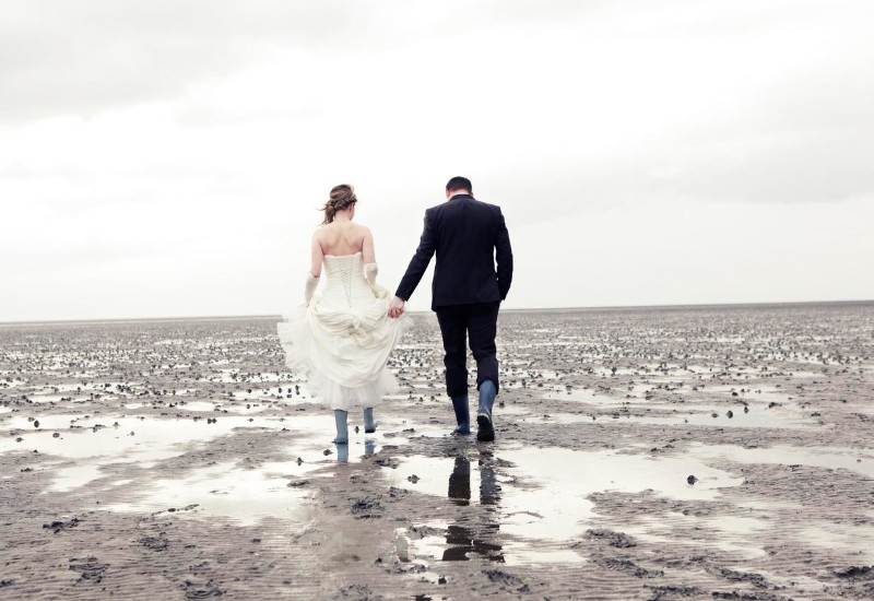 Bride and groom go in rubber boots walk in the Wadden Sea